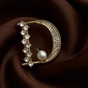 D gold tone brooch featuring a round pearl, rhinestone accents